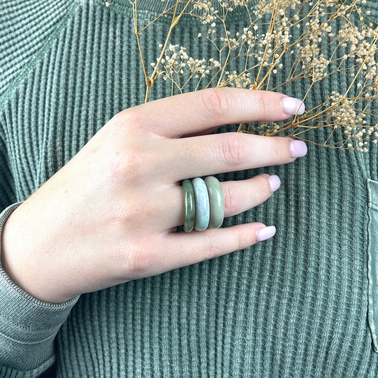 A woman wearing a green sweater displays a jade polished ring from Bliss Crystals