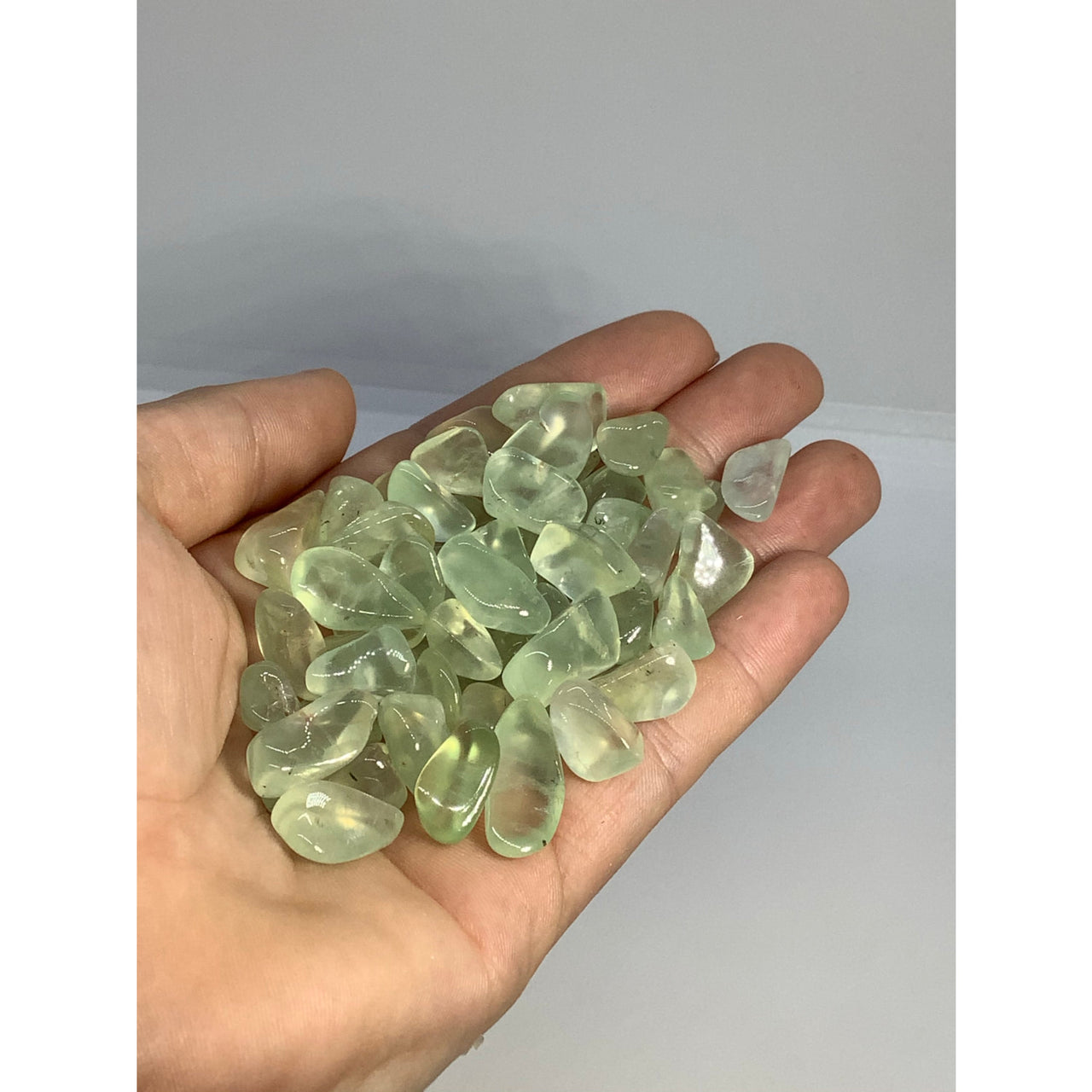 A hand holding green jade chips from a natural citrine stone parcel