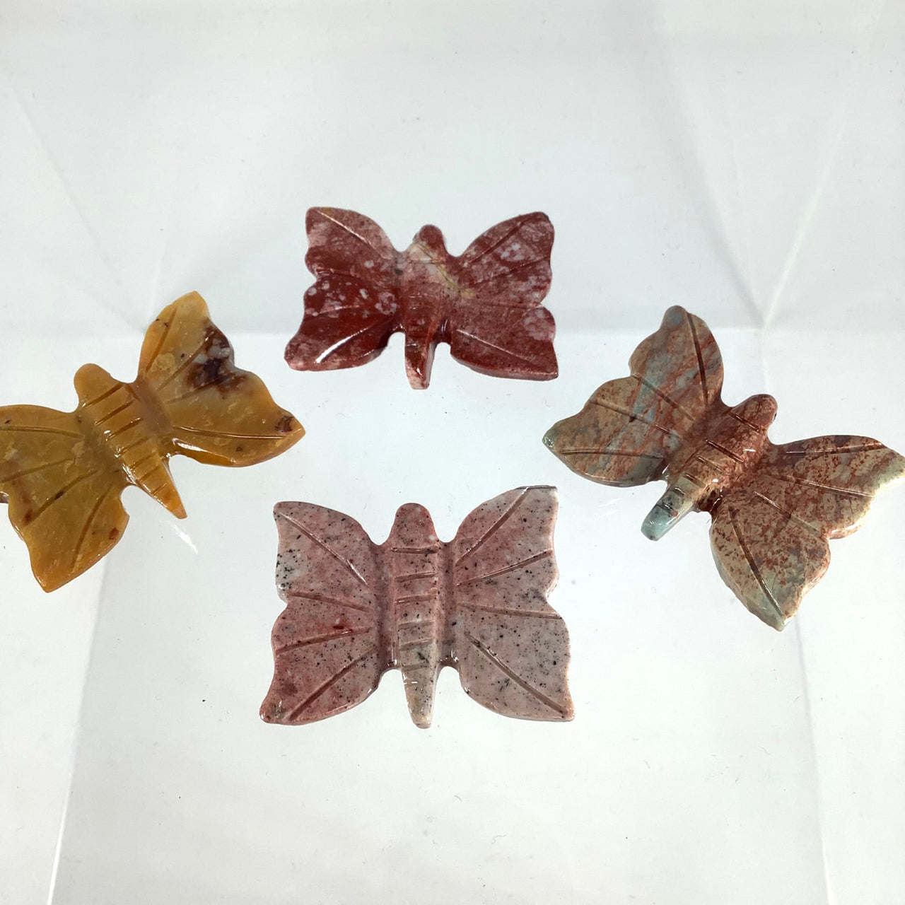 1 Soapstone Baby Animal Carving from Peru with four different colored leaves on a white surface