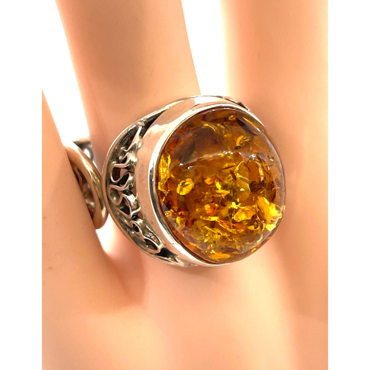 A close-up of a Baltic amber ring with a yellow stone on a finger