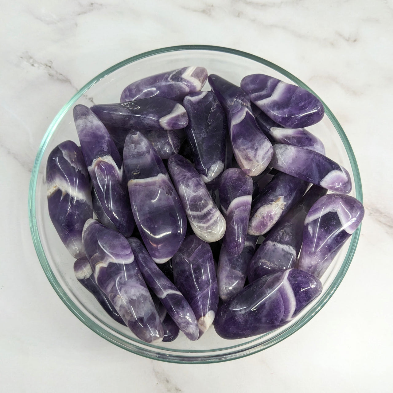 A bowl of purple Amethyst crystals; Amethyst 1.5 - 2’ Dog Tooth XL Tumbled Stone Wand #LV5760