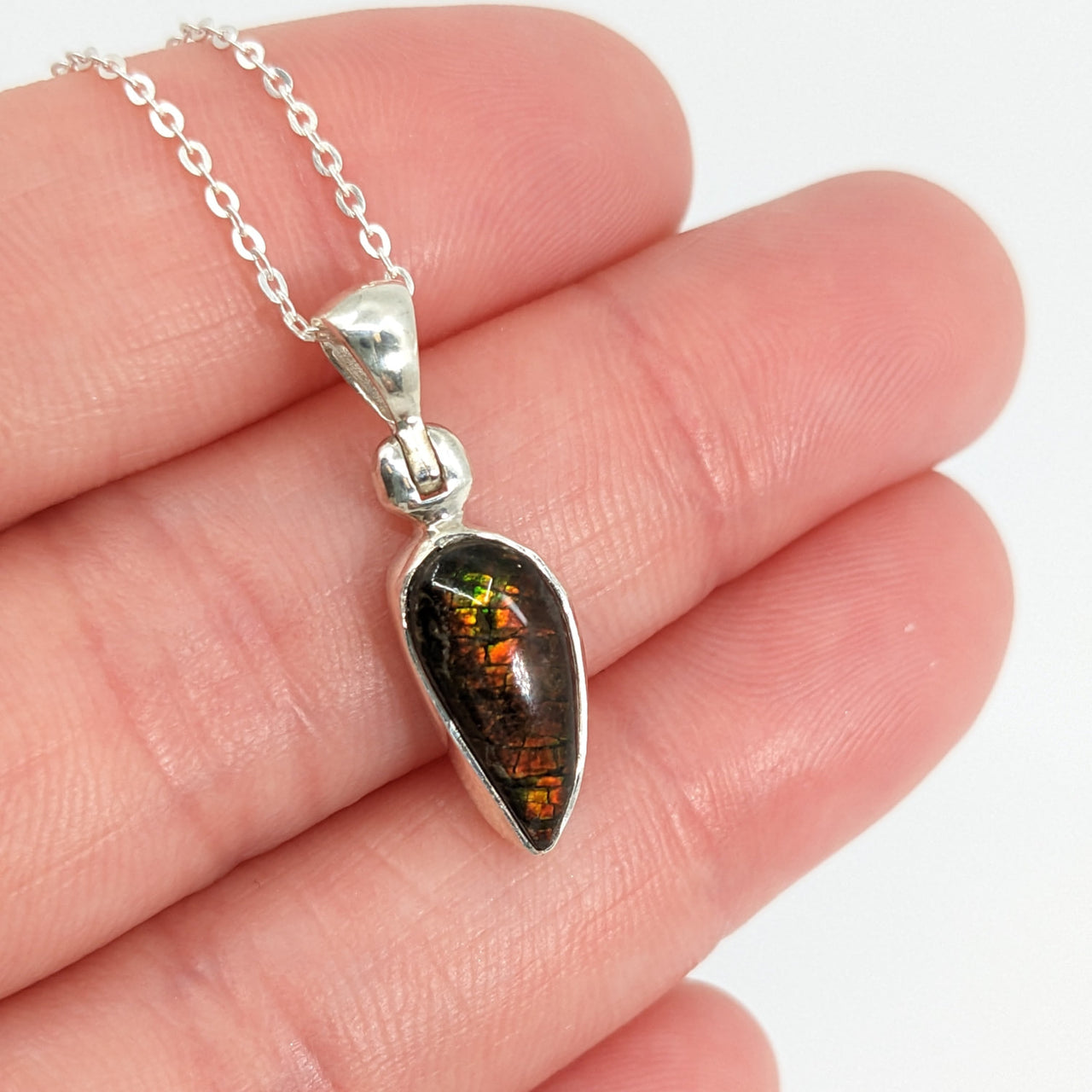 Person holding Ammolite Sterling Silver Pendant with black and green stone