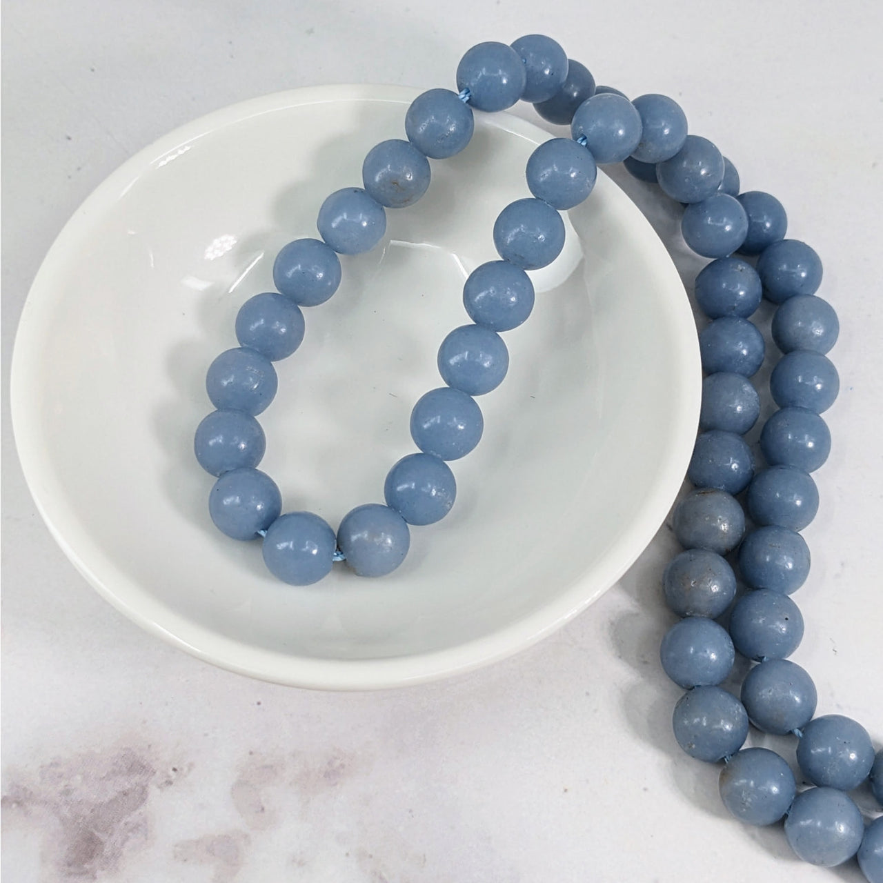 Angelite 8 mm Round Bead Strand #LV3629 displayed on a white plate