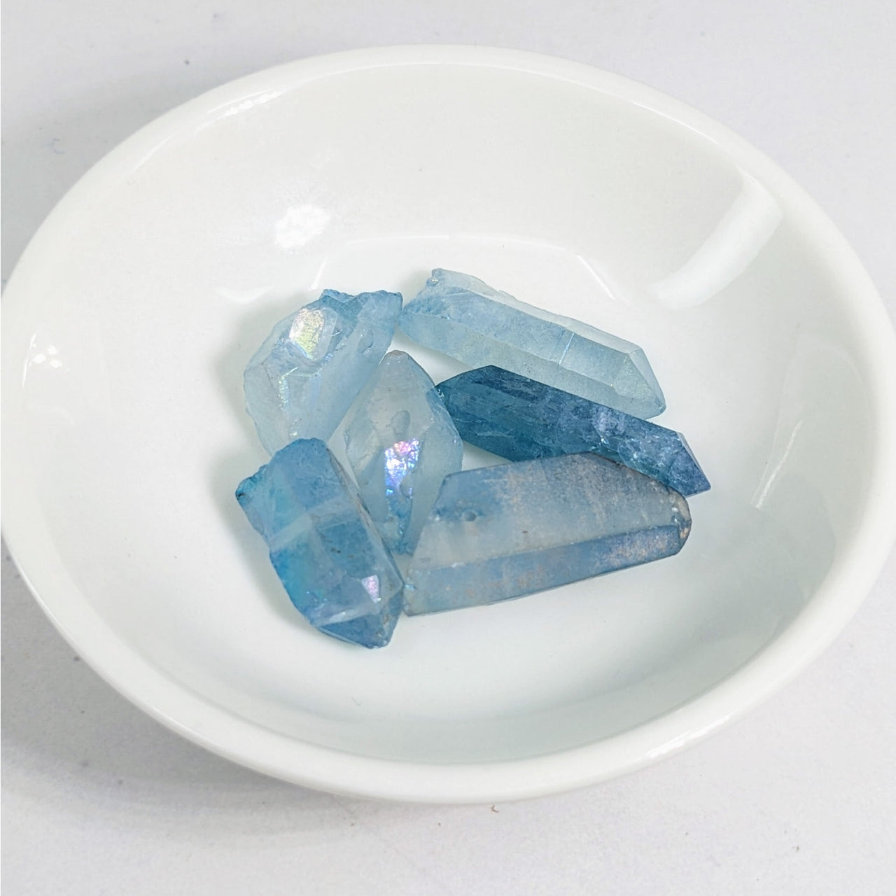 Aqua Aura Quartz Point Top Drilled Bead 6 pack LV3631 in a white bowl with blue crystals