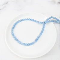 Thumbnail for Aquamarine 4 mm Round Bead Strand #LV3634 on a white plate