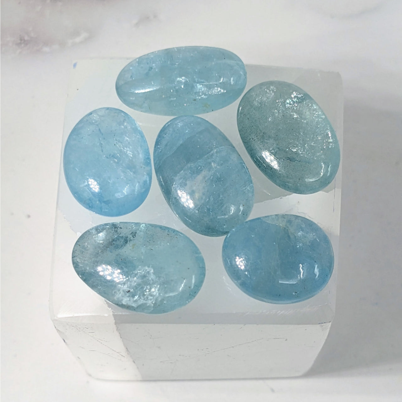 Aquamarine A+ Polished Stone #LV3887: Five Blue Stones in a White Box on a Table