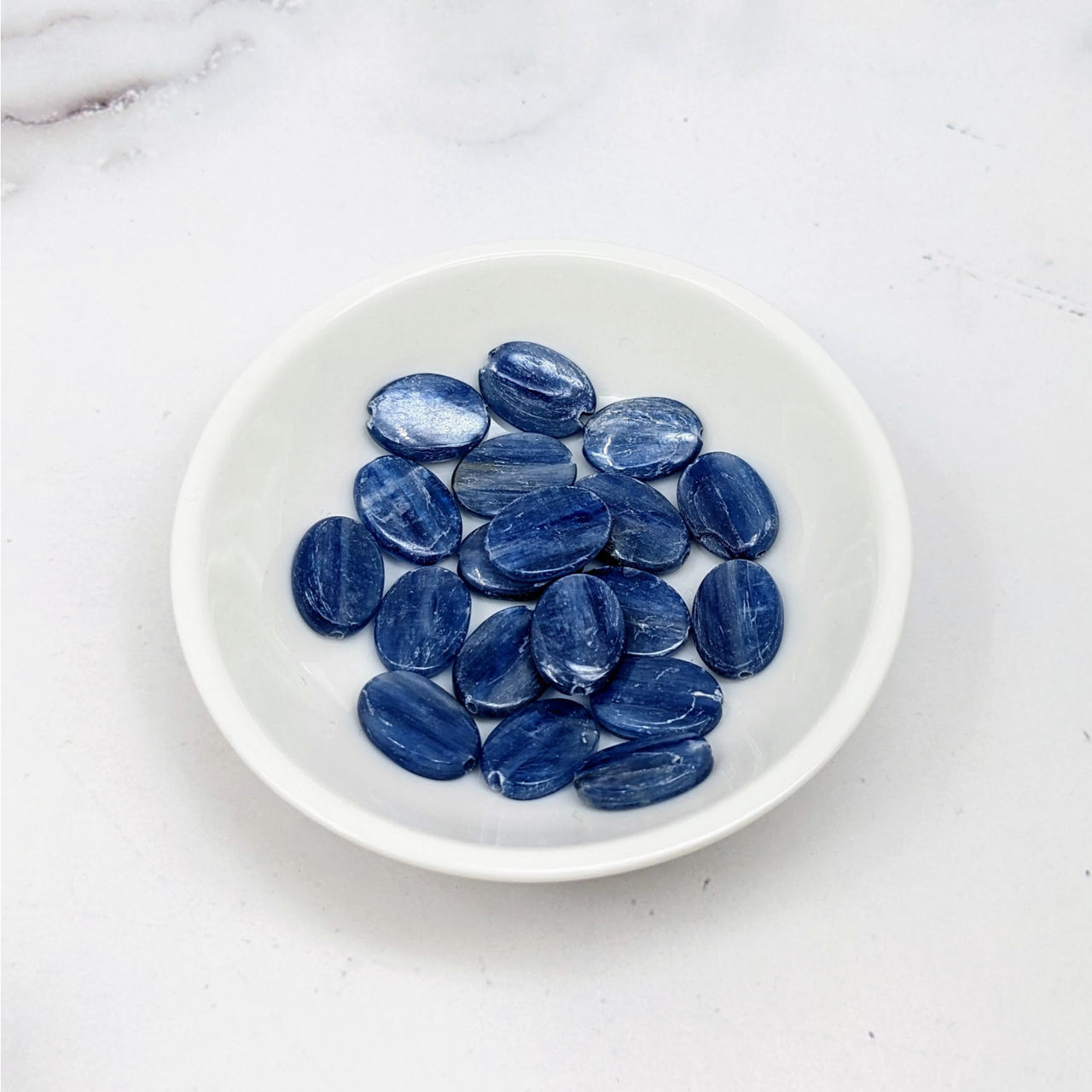 Blue Kyanite Flat Oval Bead 2 Pack #LV3664 displaying blue sapphire gems in a white bowl