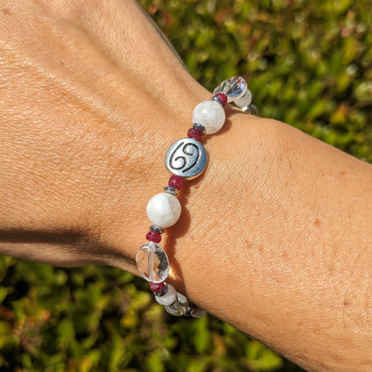 Woman’s hand wearing Cancer Zodiac Handmade Beaded Bracelet in white and red beads