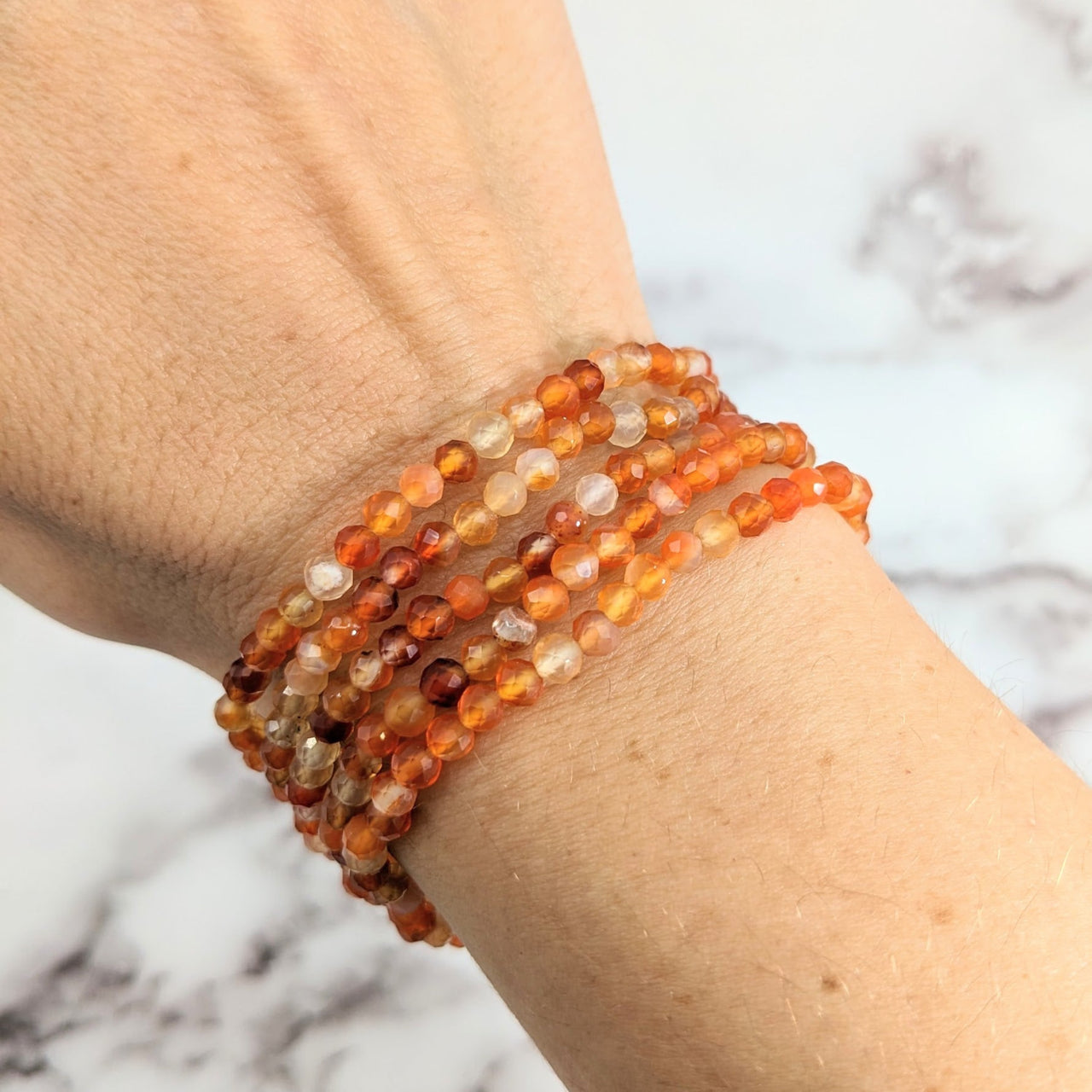 Close-up of a person wearing a Carnelian 7’ Faceted 4mm Bracelet #LV1925 with beads