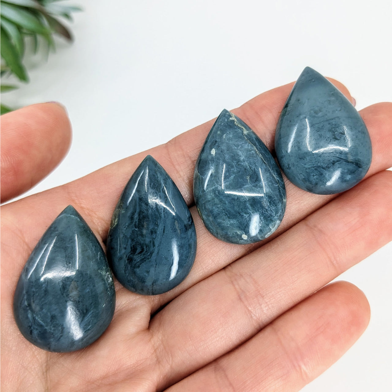 Close-up of hands holding blue Dianite Blue Jade 1.2’ Cabochon stones, product #LV3368