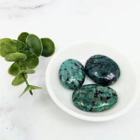 Thumbnail for Three green palm stones in a white bowl next to a plant, part of Emerald 1 Collection