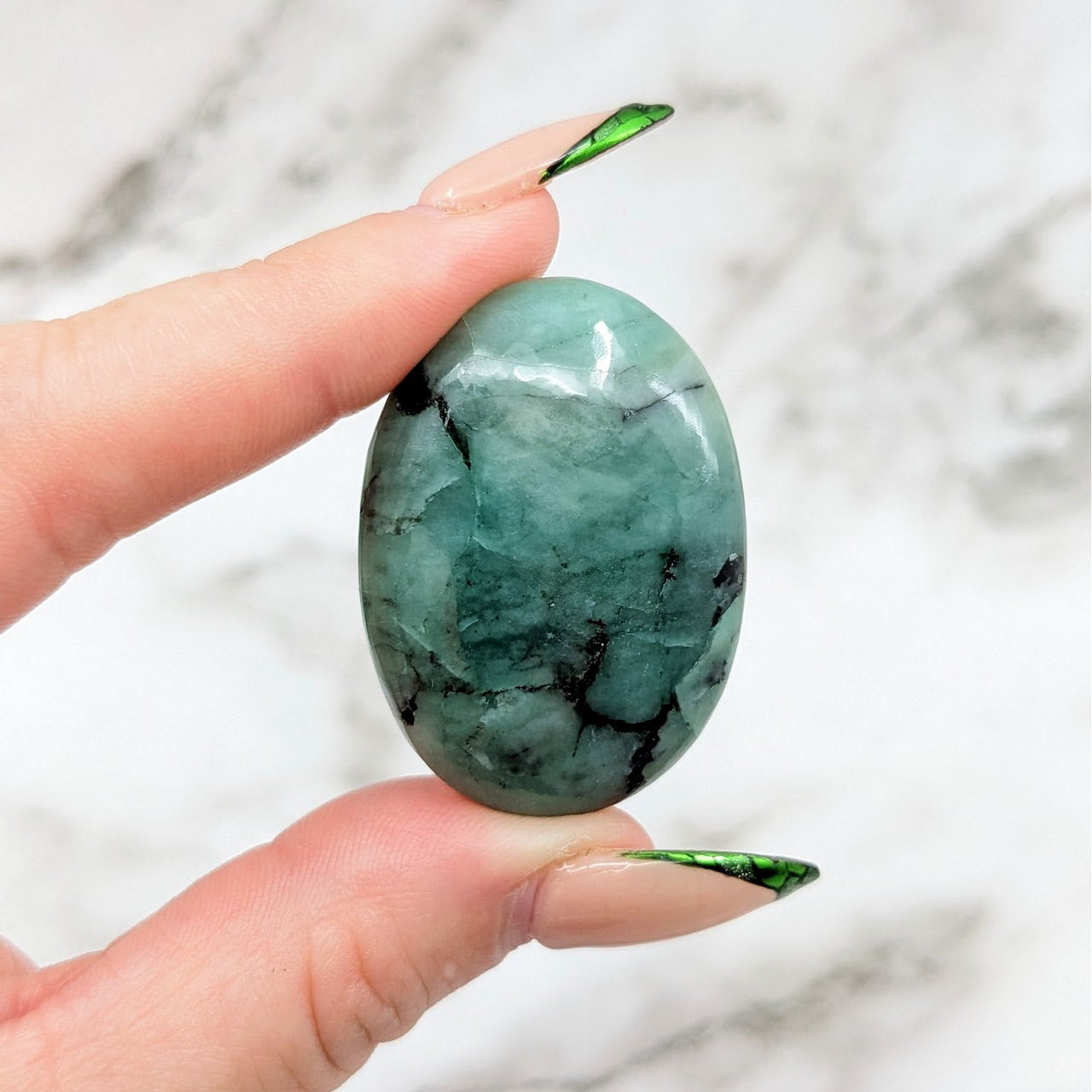 A person holding an Emerald 1.5’ Palmstone #LV4565 green gem