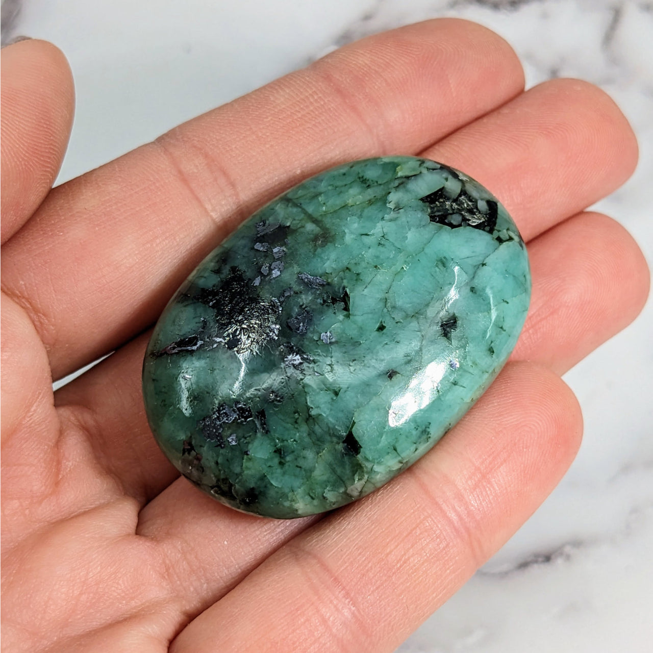 A green jade stone in a hand, featured in Emerald A+ Palm #LV3839