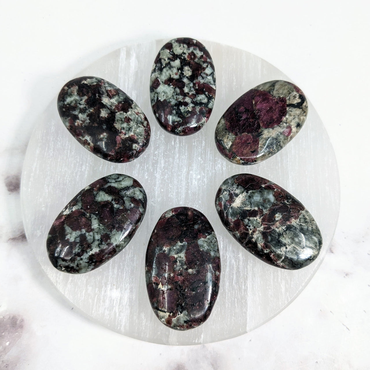 Eudialyte palm stones on a white plate on marble surface, perfect for energy healing