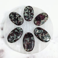 Thumbnail for Eudialyte palm stones on a white plate on marble surface, perfect for energy healing