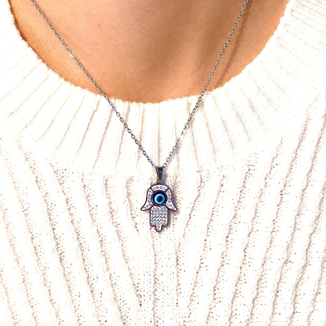 Close up of a person wearing the Evil Eye Hamsa Necklace from product #J746