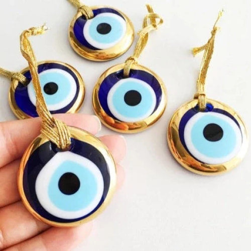 Hand holding blue and white evil eyes, product: Evil Eye Wall Hangings #Q224