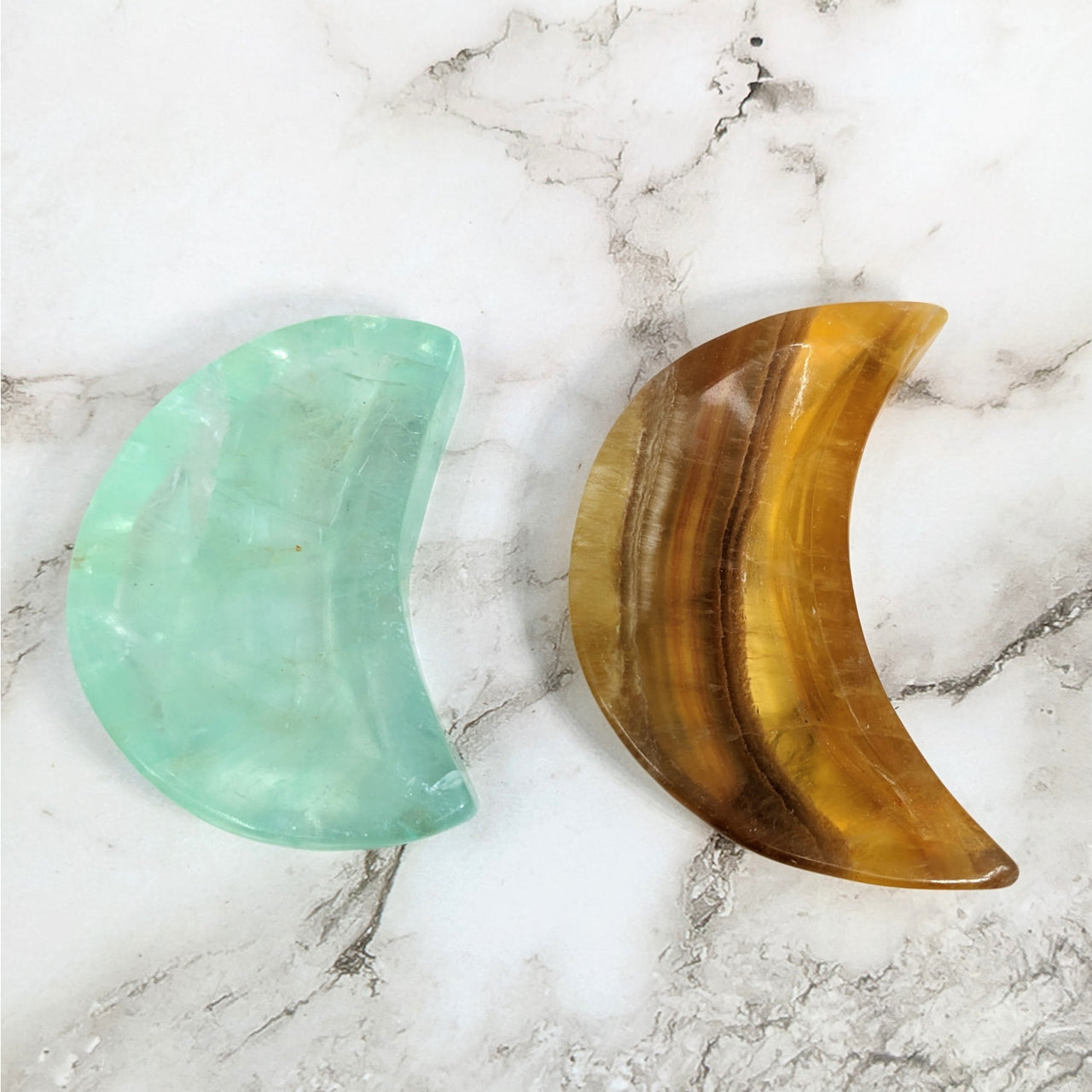 Fluorite 3.4-3.7’ Moon Bowl #LV4142: Two green and yellow glass crescents on marble surface