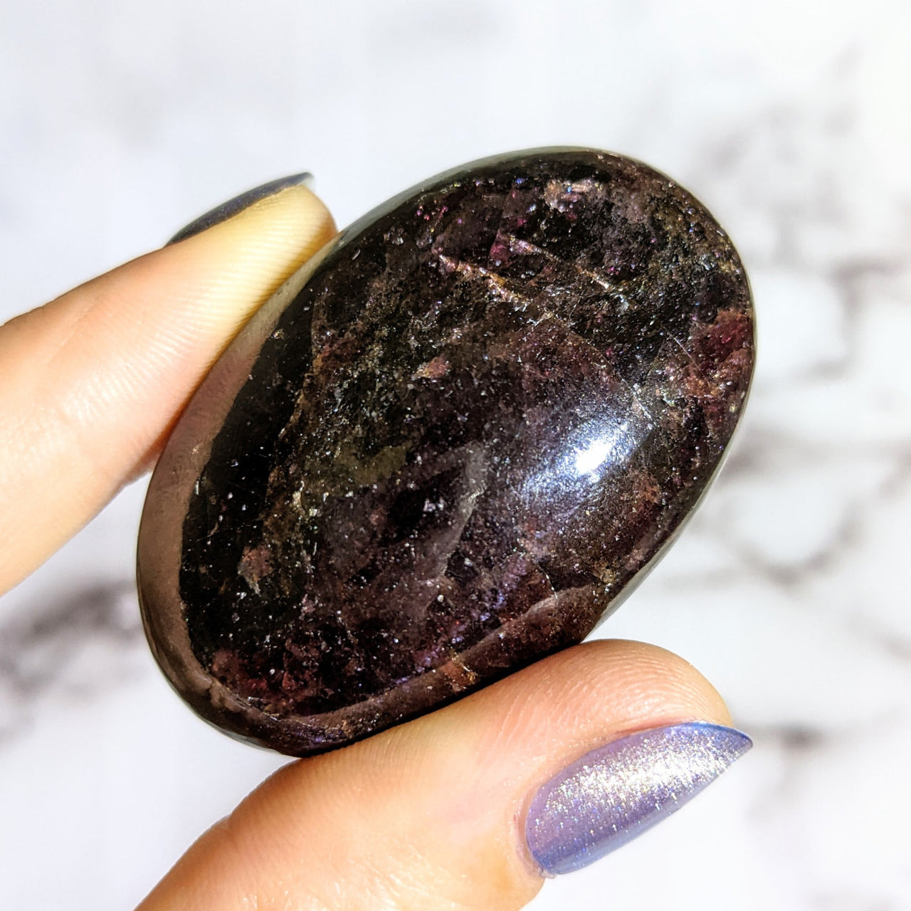 A person holding a Garnet aka Almandine 1.8-1.9’ Palm Stone #LV1428