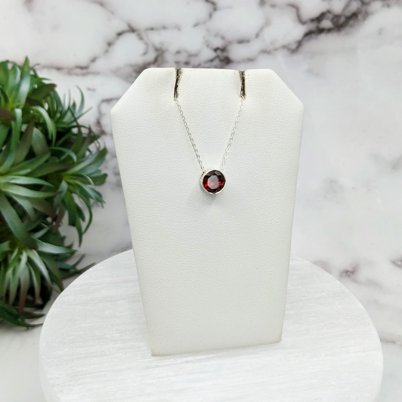 Close-up of Garnet Faceted Necklace with Sterling Silver Slider Pendant on Display with Plant