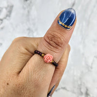 Thumbnail for A woman’s hand with blue and white manicure featuring a rose, wearing Garnet Flower Beaded Ring