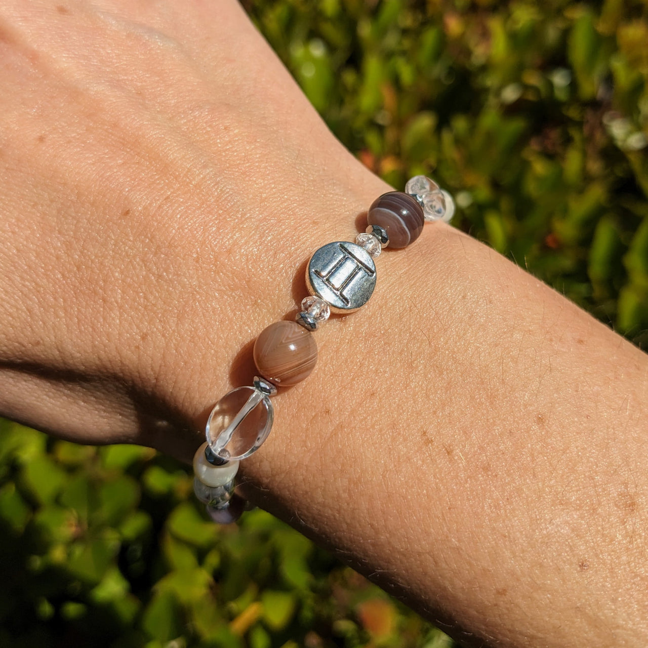 A woman’s hand with a Gemini Zodiac Handmade Bracelet featuring hematite spacer beads