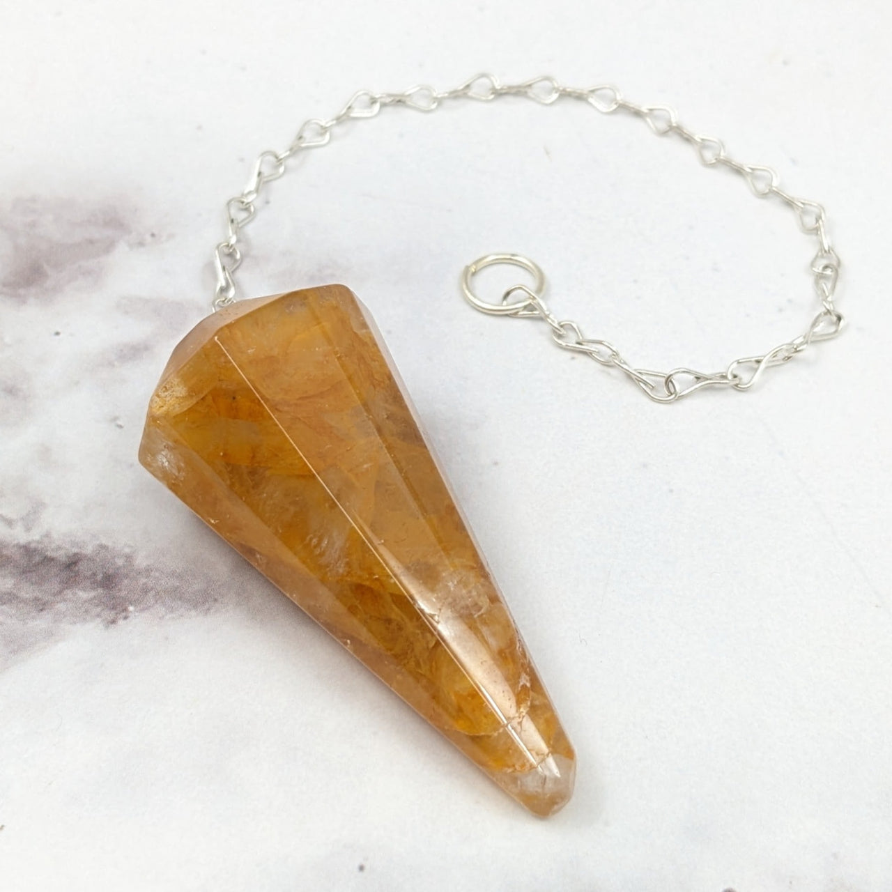 Close-up of the Golden Healer Pendulum #J861, a stone pendulum on a chain