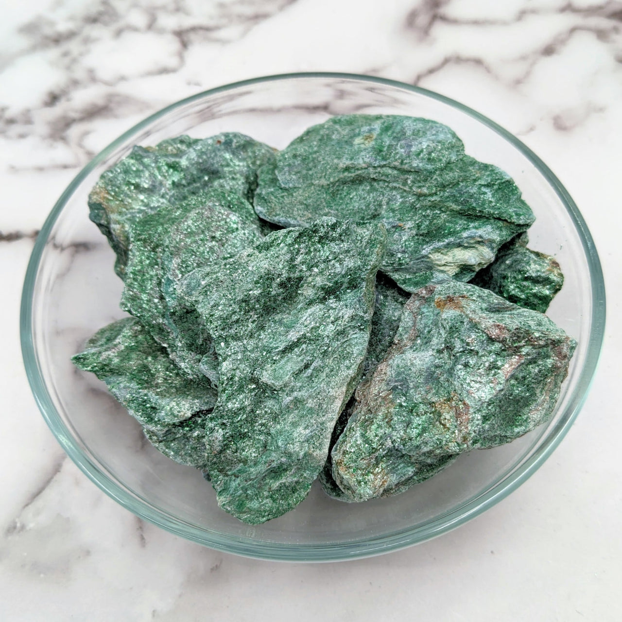 Close-up of Green Fuchsite Rough Stone in a bowl on a marble counter, product #LV1498