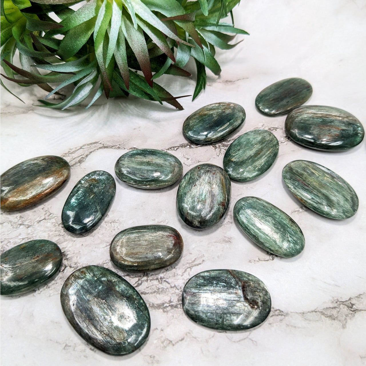 A close-up of Green Kyanite palm stones on a table; product: Mini Palm #LV5136