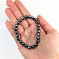 Thumbnail for Hand holding Hematite Bracelet, Style #J258, showcasing its sleek black and white design