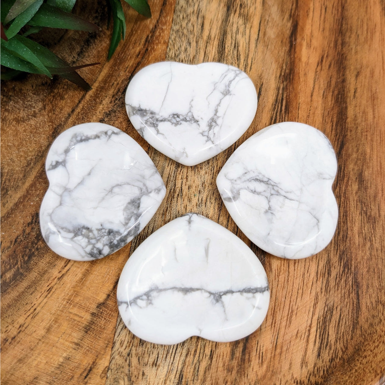 Howlite 1.5’ heart thumb stones (#LV4304) on wooden table, white marble texture