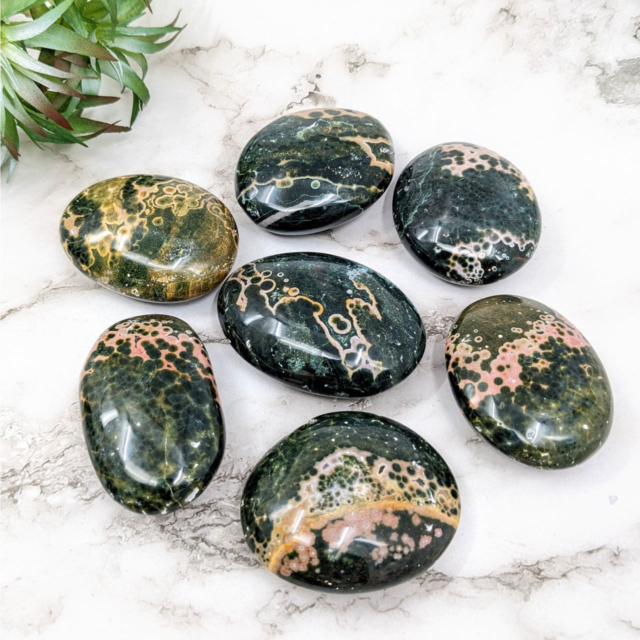 A group of green and gold Kabamby Ocean Jasper pebbles on display