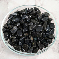 Thumbnail for A bowl of tumbled black stones from South Africa on a marble counter