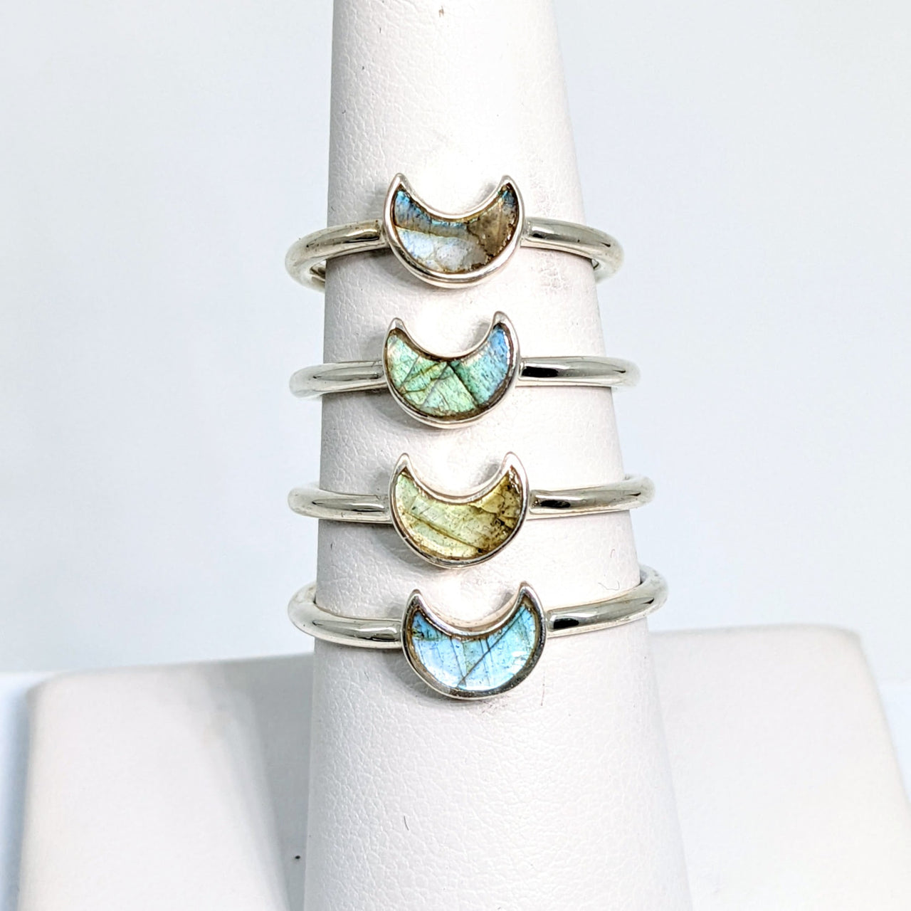 Close-up of a stack of Bliss Crystals rings with labradorite mini crescent moon and colored stones