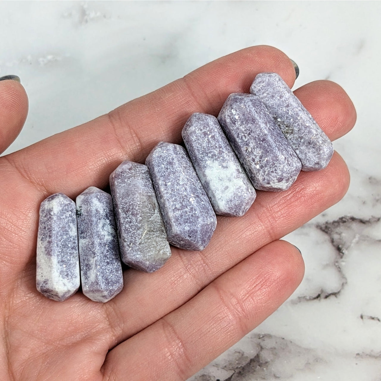 Hand holding five large gray and white quartzite stones, Lepidolite Mini DT Wand #LV1931