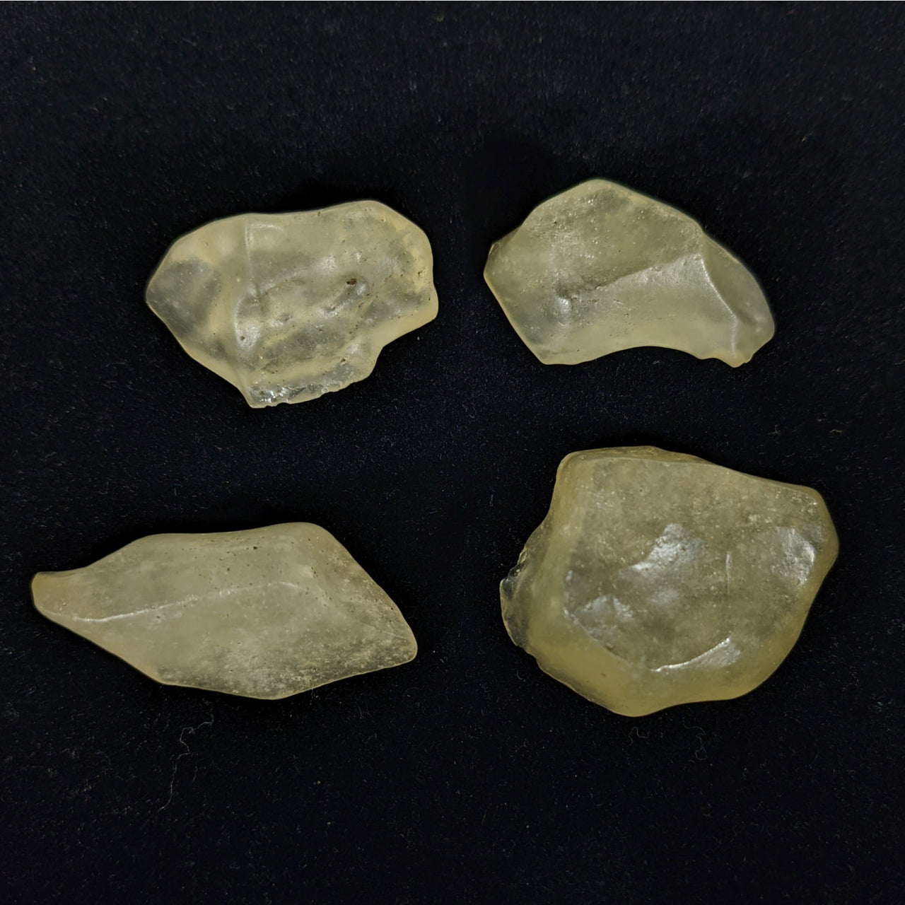 Three pieces of Libyan Desert Glass on a black surface - Rough #R215, yellow quartz stones