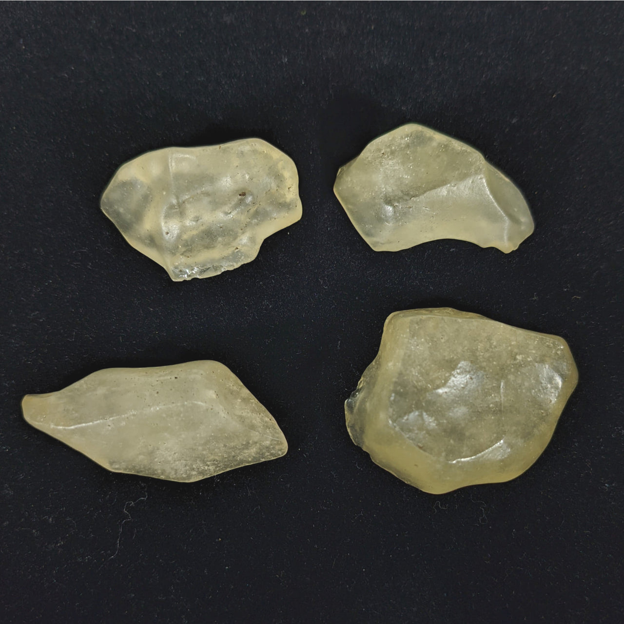 Three pieces of Libyan Desert Glass on a black surface - Rough #R215