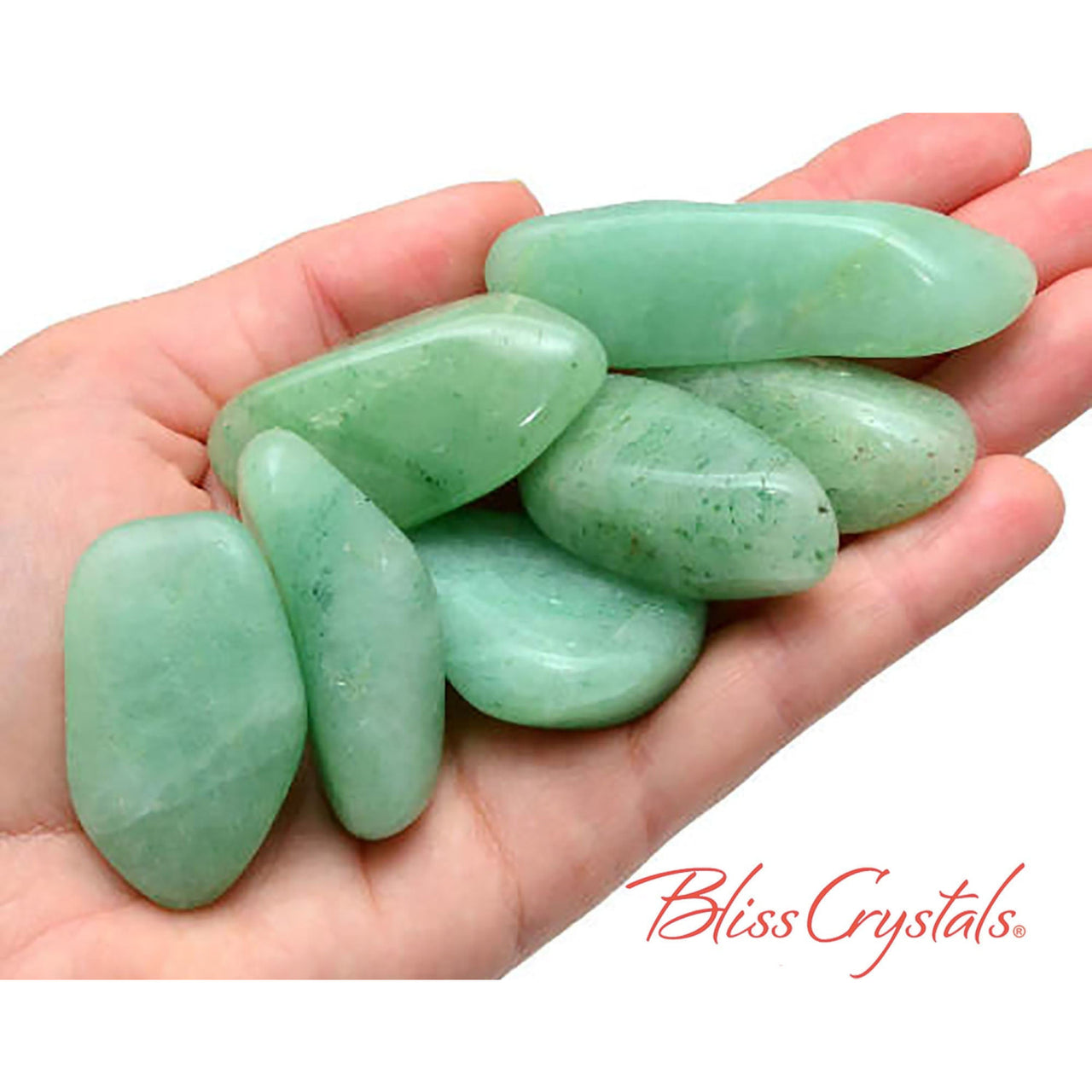 A hand holding a bunch of green aventurine tumbled stones for prosperity