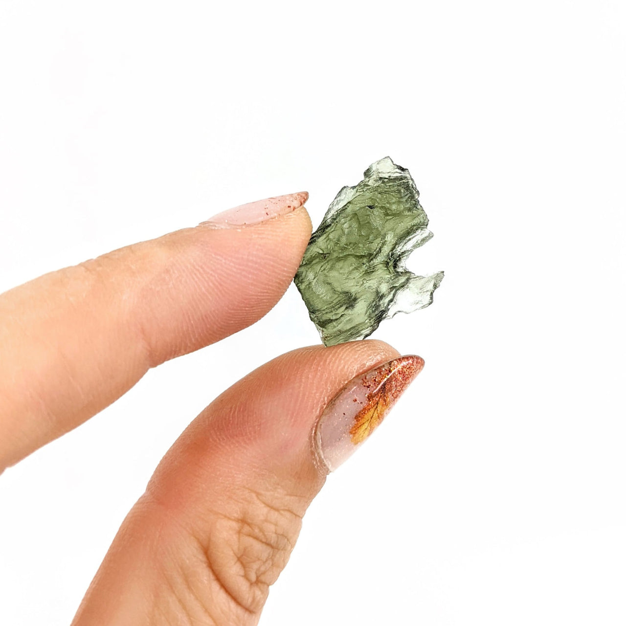 A hand holding a piece of green moss-like Moldavite Raw from Czech Republic, 2.013g Rough #SK0545