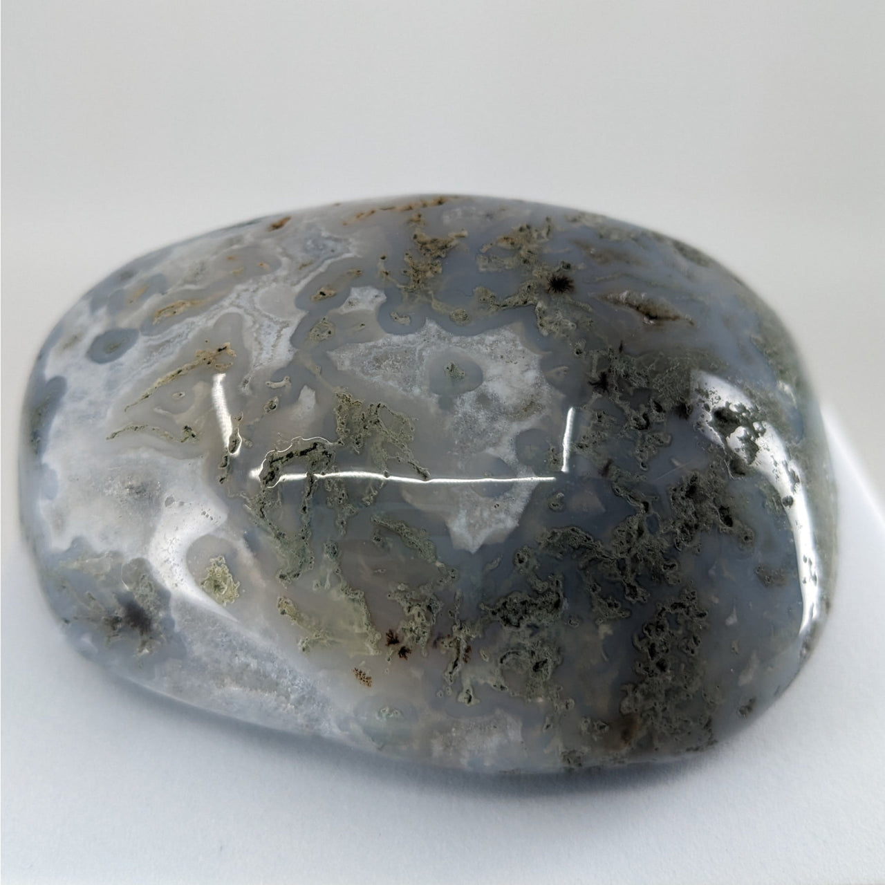 Moss agate touchstone P165 with a ruffled design and thin line on a table