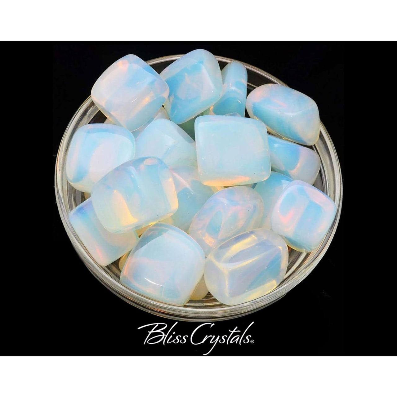 Frosted glass bowl filled with white opalite tumbled stones on black background