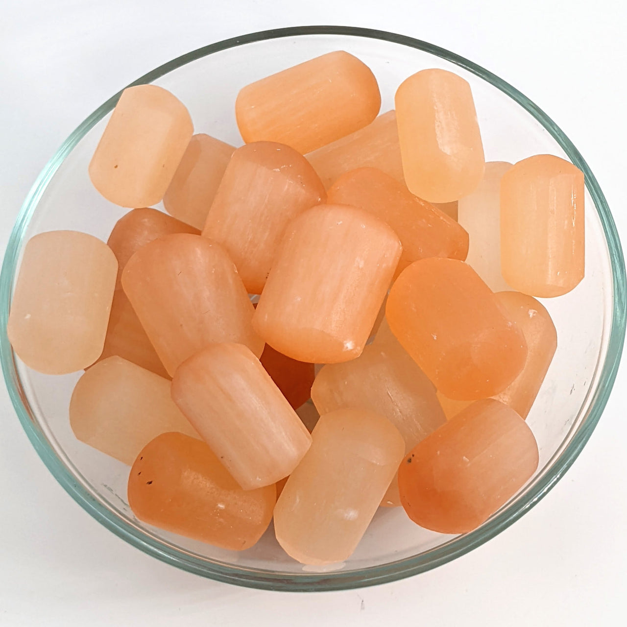 A bowl of orange-colored Peach Selenite tumbled stones, product code #SK9256