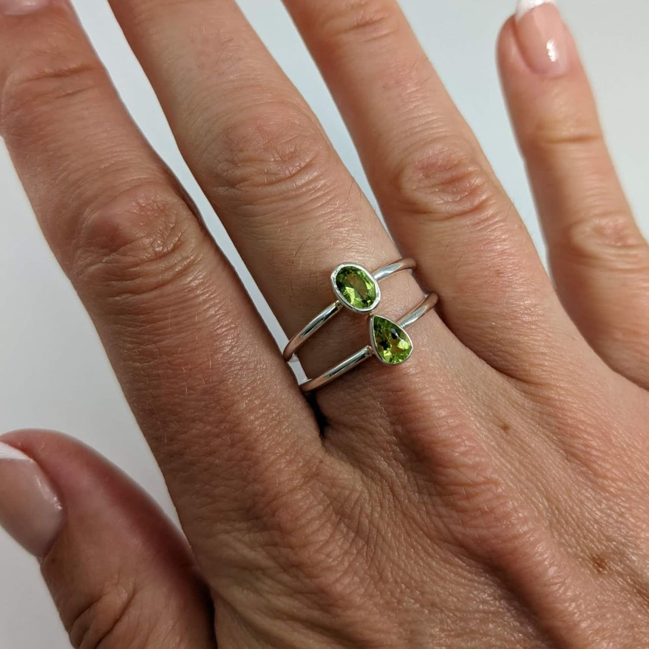 A woman’s hand wearing the Peridot Dainty Sterling Silver Stackable Ring #J518