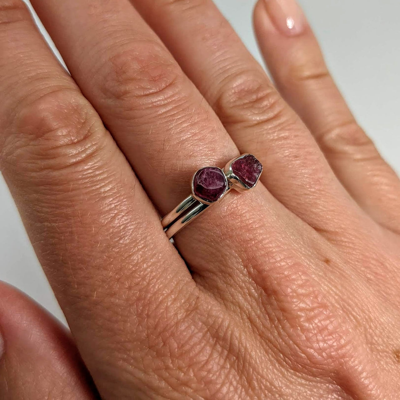 A woman’s hand wearing a pink tourmaline sterling silver ring, #SK7300 stackable and dainty