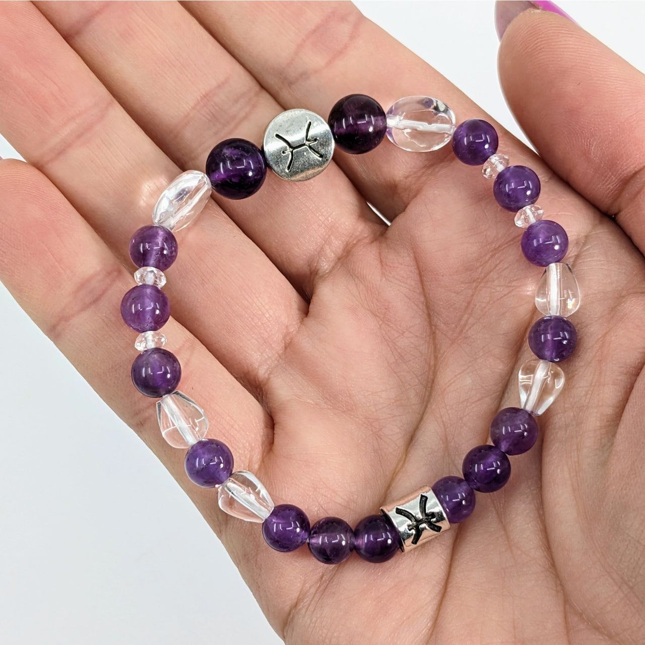 A person holding a Pisces Zodiac Handmade Beaded Bracelet with silver cross