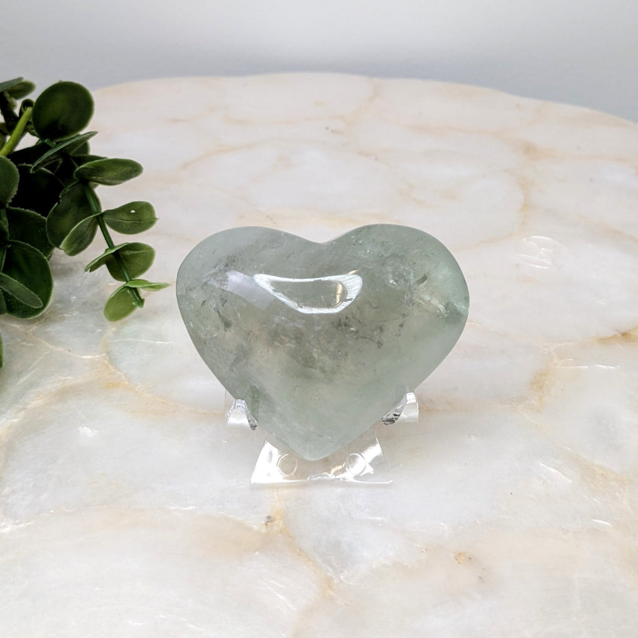 Heart-shaped green quartz stone on white marble table - Prasiolite 2.5’ Heart #LV4857