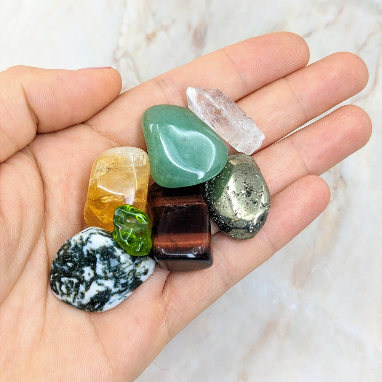 Hand holding colorful gems from Prosperity Crystal Companion Set for Abundance Wealth Success