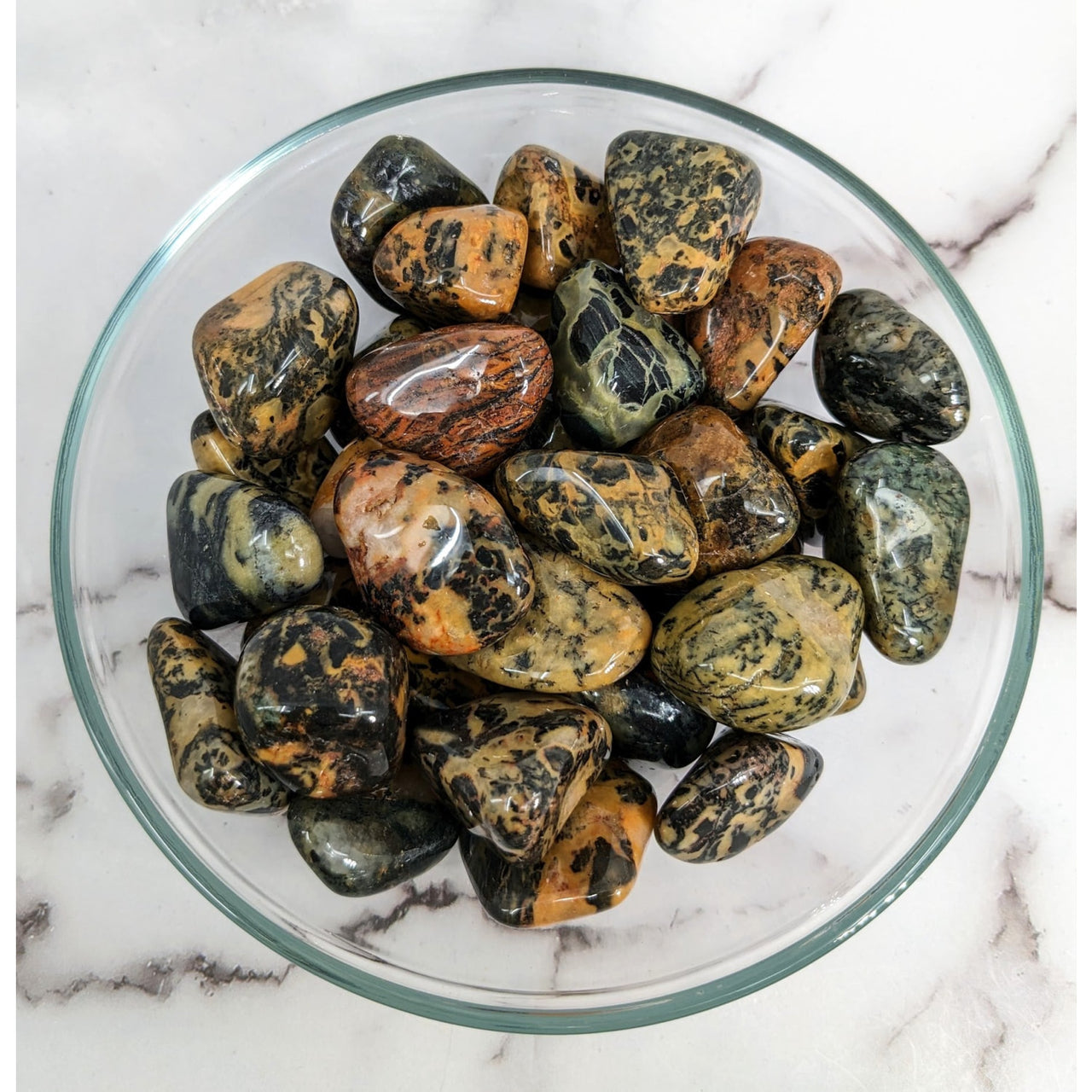 Puff Adder Jasper tumbled stones in a bowl, showcasing green and yellow marble patterns