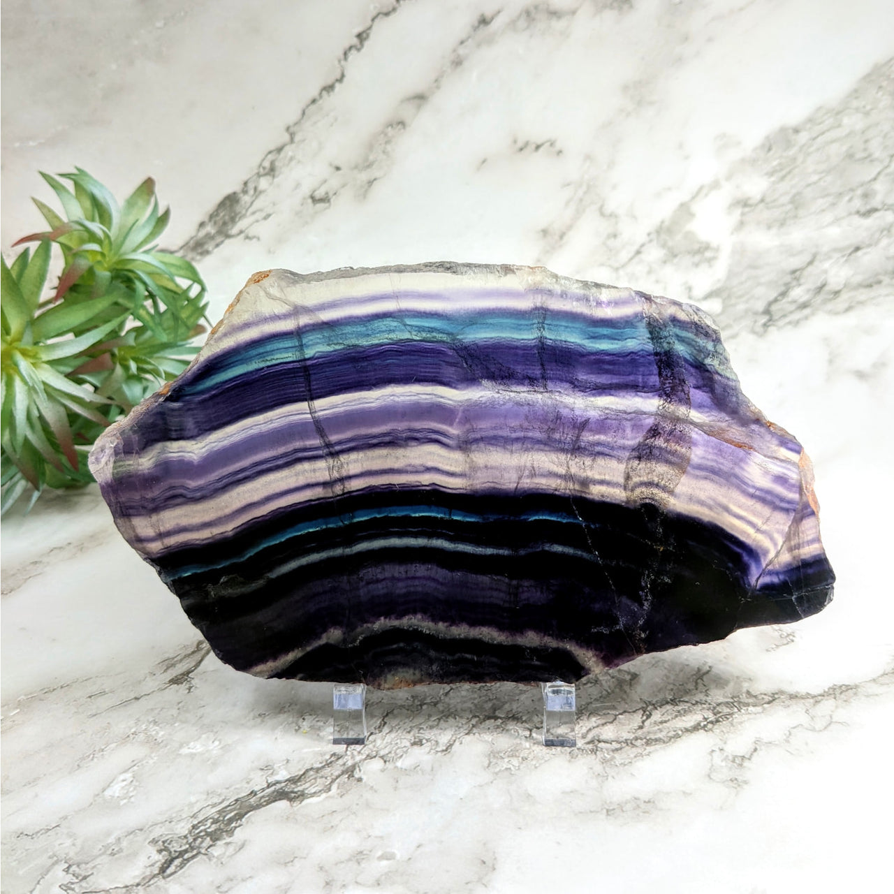 Close-up of a purple and blue striped Rainbow Fluorite slab on a marble surface