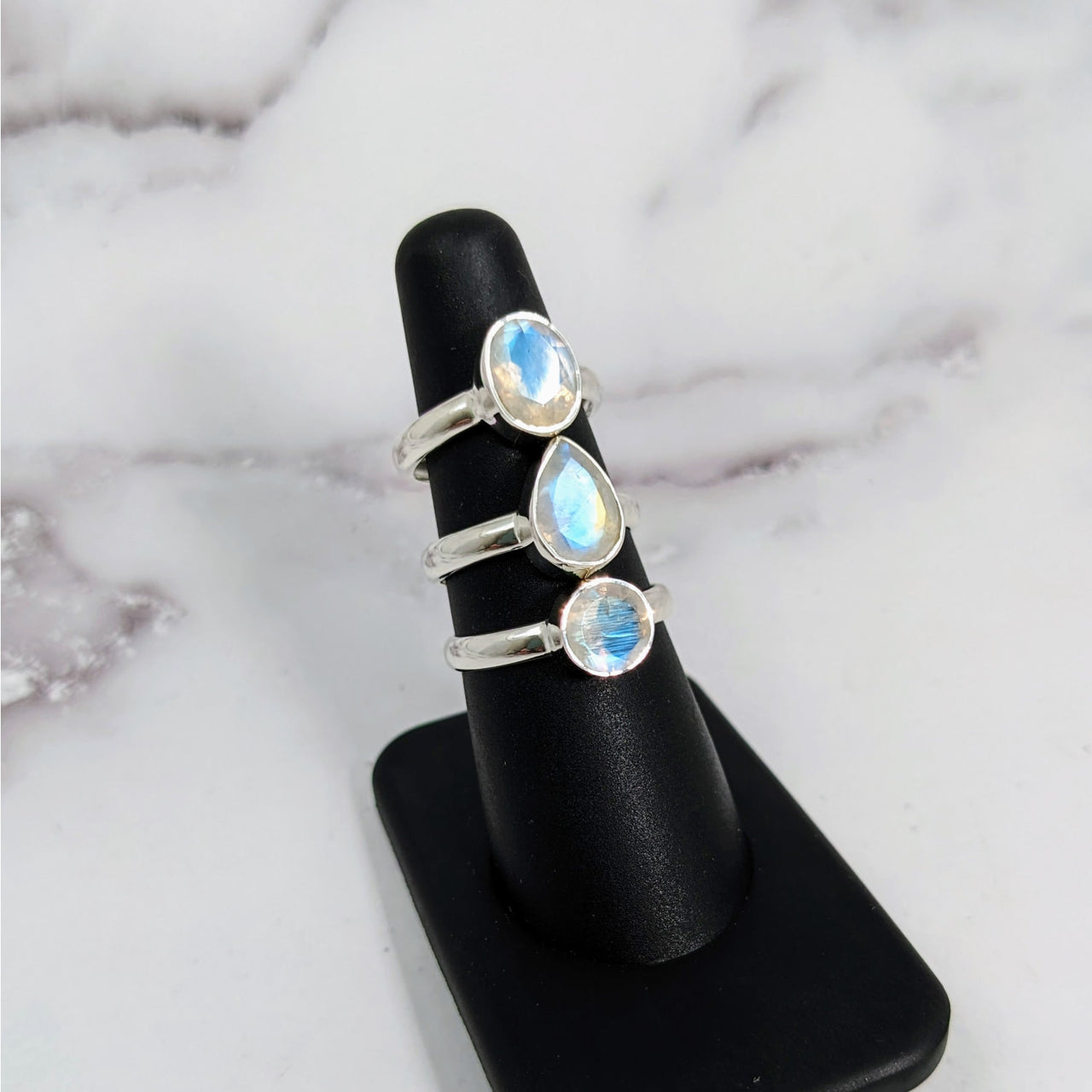 Rainbow Moonstone Faceted S.S Ring #LV3912 with three stones displayed on a stand